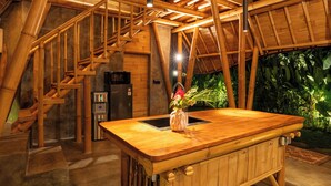 A bamboo-themed interior with a central wooden island, a built-in sink, and a staircase. - Damuh Alam (Sukasada)