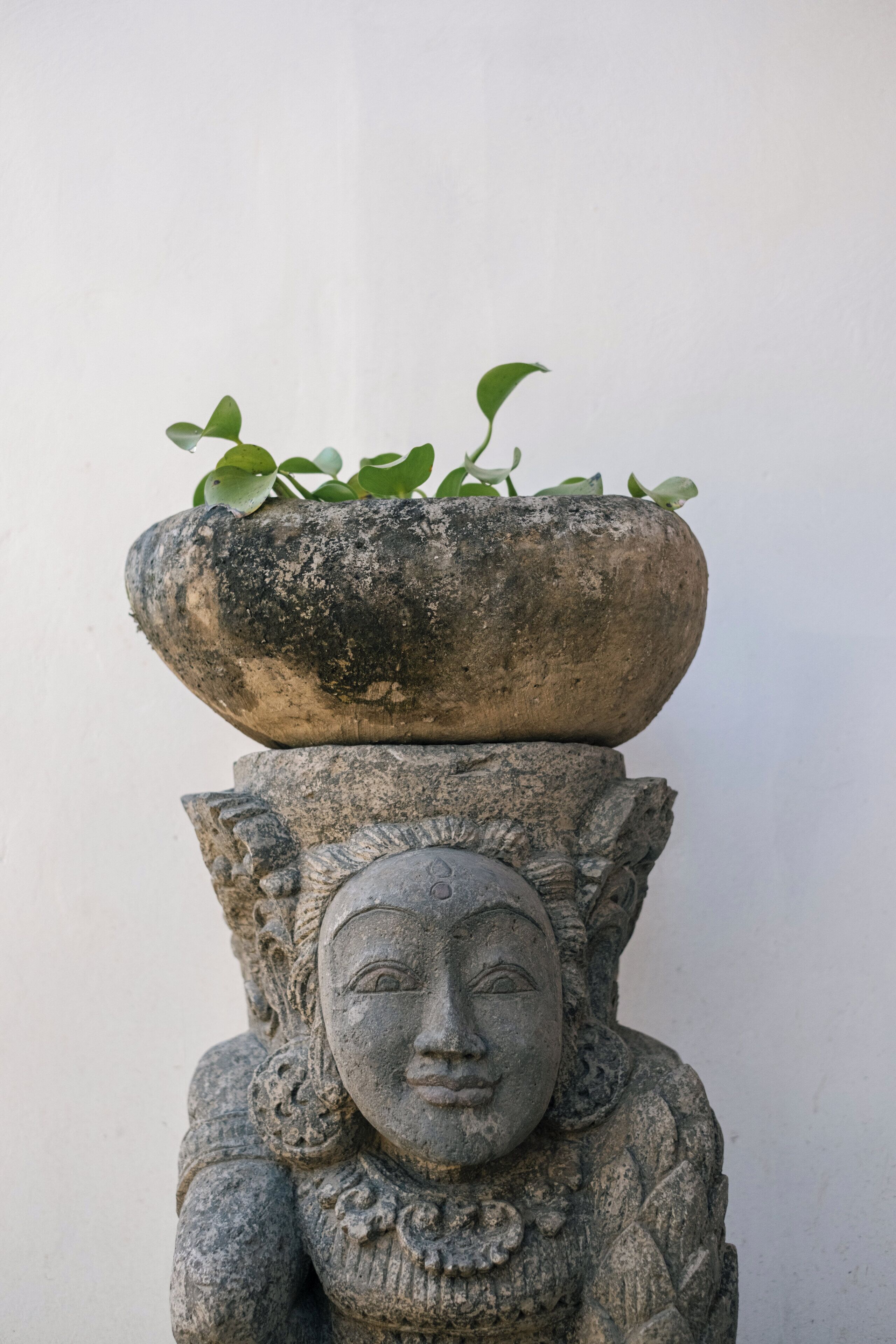 A stone sculpture with a plant pot on top.