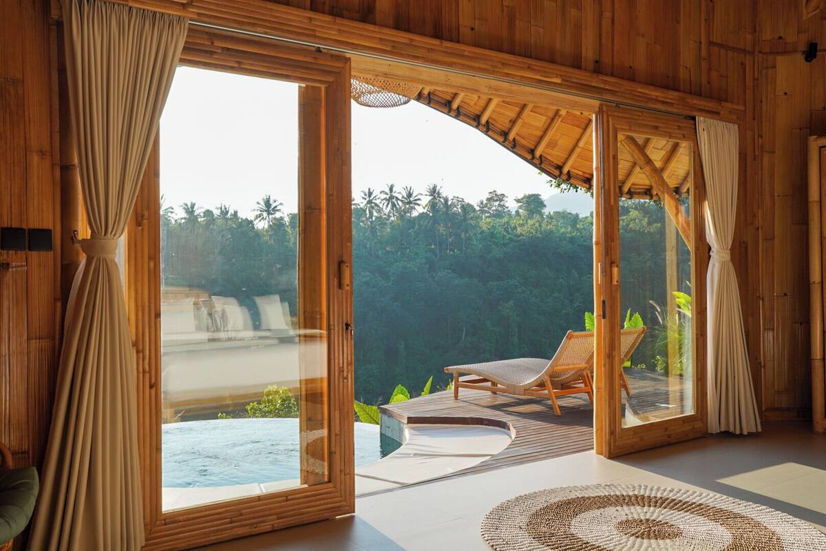 A wooden room with a glass door leading to a pool and a lounge chair.