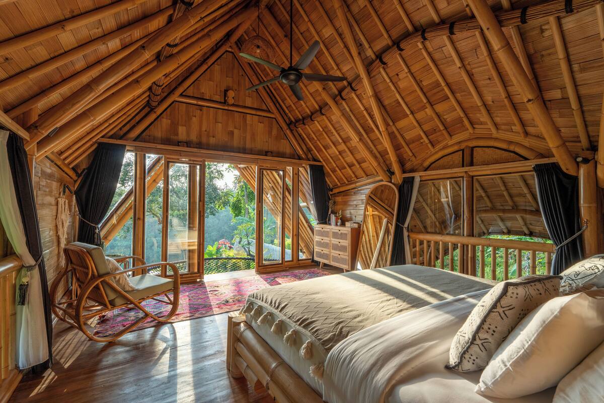 A spacious room with a large bed, a rocking chair, and a balcony with a view of the outdoors.