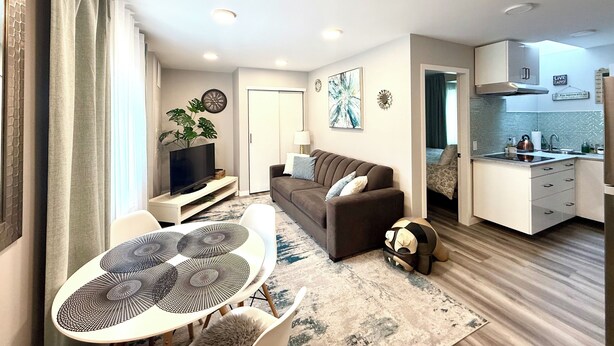 A modern living room with a sofa, TV, and dining area.