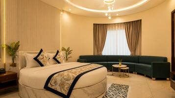 A modern bedroom with a large bed, a green sofa, a small round table, and a decorative rug.