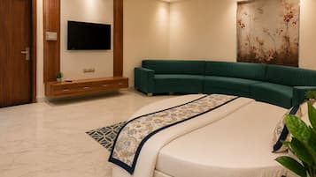 Un dormitorio moderno con una cama grande, un sofá modular verde, un televisor de pantalla plana y un elemento decorativo en la pared.