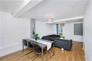 A modern living space with a dining area, a sofa, and a view of the outdoors. - Spacious 6-Bed Home Sleeps 12 Near Highfields Park (Nottingham)