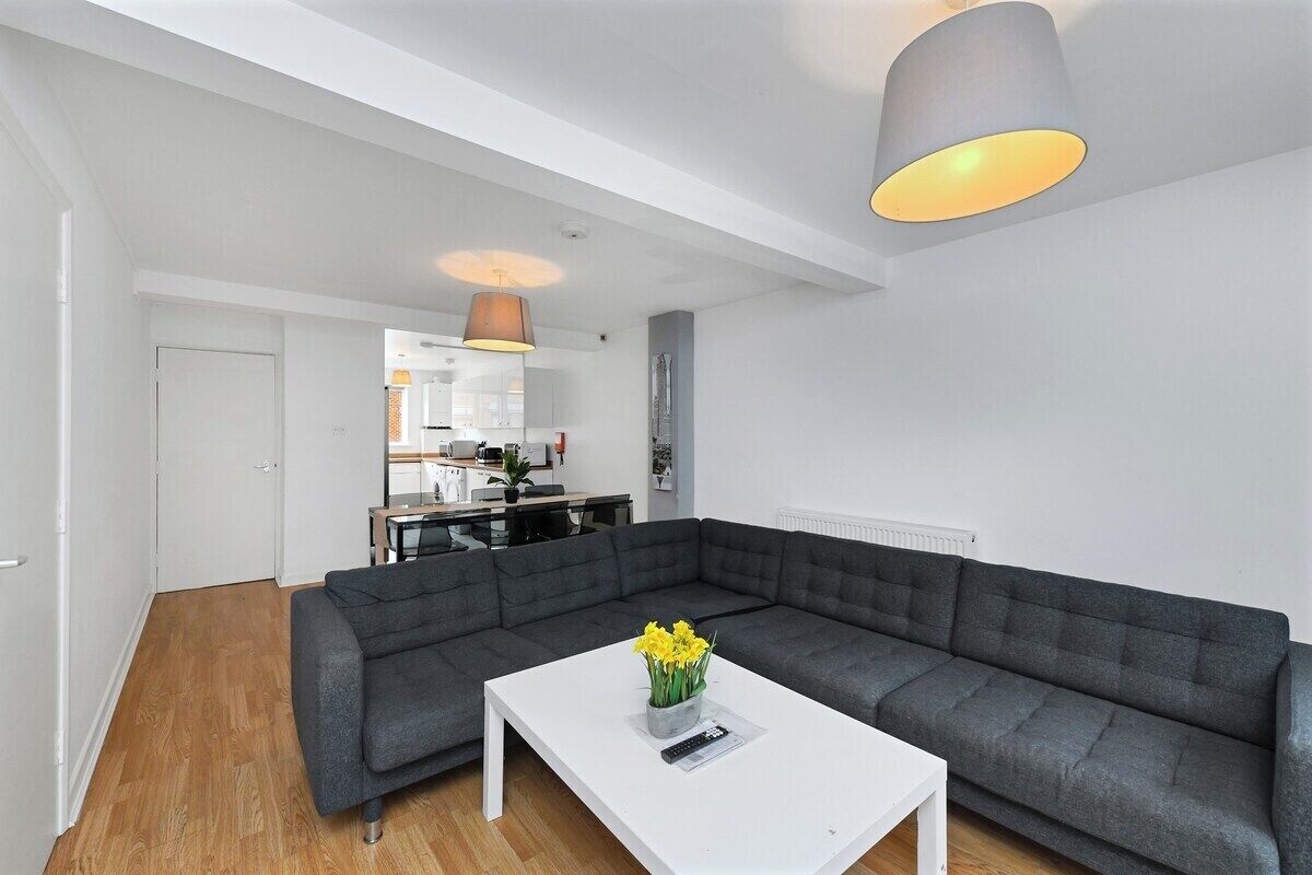 Ein modernes Wohnzimmer mit einem grauen Ecksofa, einem weißen Couchtisch und einer Pendelleuchte.