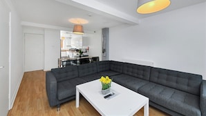 A modern living room with a grey sectional sofa, a white coffee table, and a pendant light.