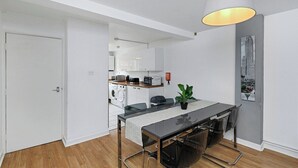 Une cuisine moderne avec des meubles blancs et un coin repas comprenant une table et des chaises.