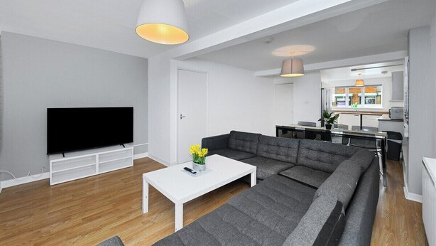 A modern living room with a flat-screen TV, a white coffee table, and a grey sectional sofa.
