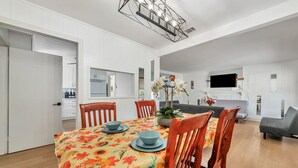 Un comedor moderno con mantel floreado, sillas de madera y una araña.