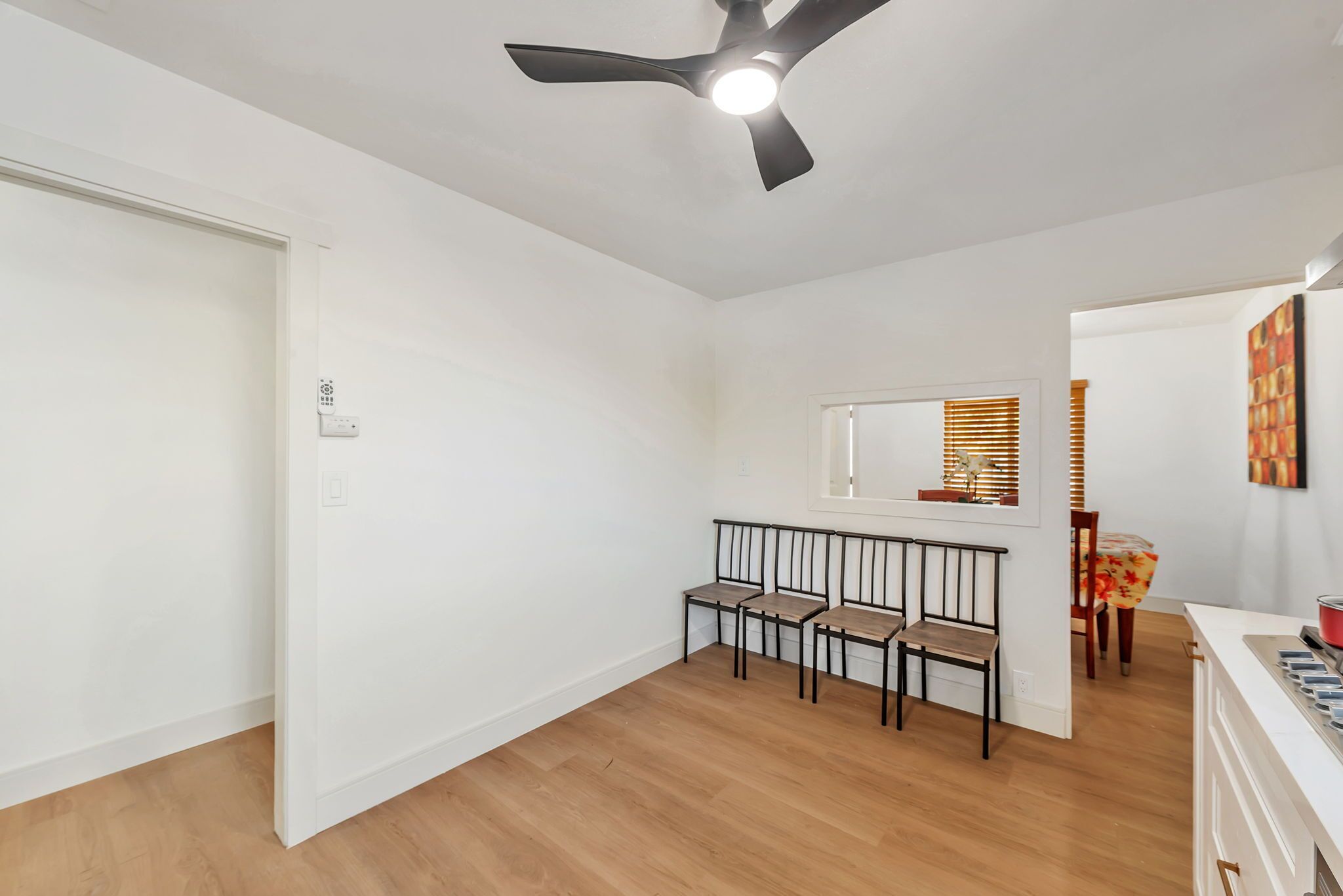 A room with a ceiling fan, a dining area with a table and chairs, and a window with blinds.