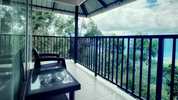 Un balcon doté d’une paroi en verre, d’une table et d’une chaise.