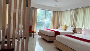 Une chambre d’hôtel avec deux lits, un ventilateur de plafond et de grandes fenêtres avec des rideaux.