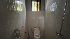 Um banheiro pequeno, com azulejos, incluindo vaso sanitário, chuveiro e janela com grades.
