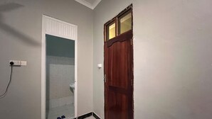 Casa de banho com sanita, espelho e porta de madeira.