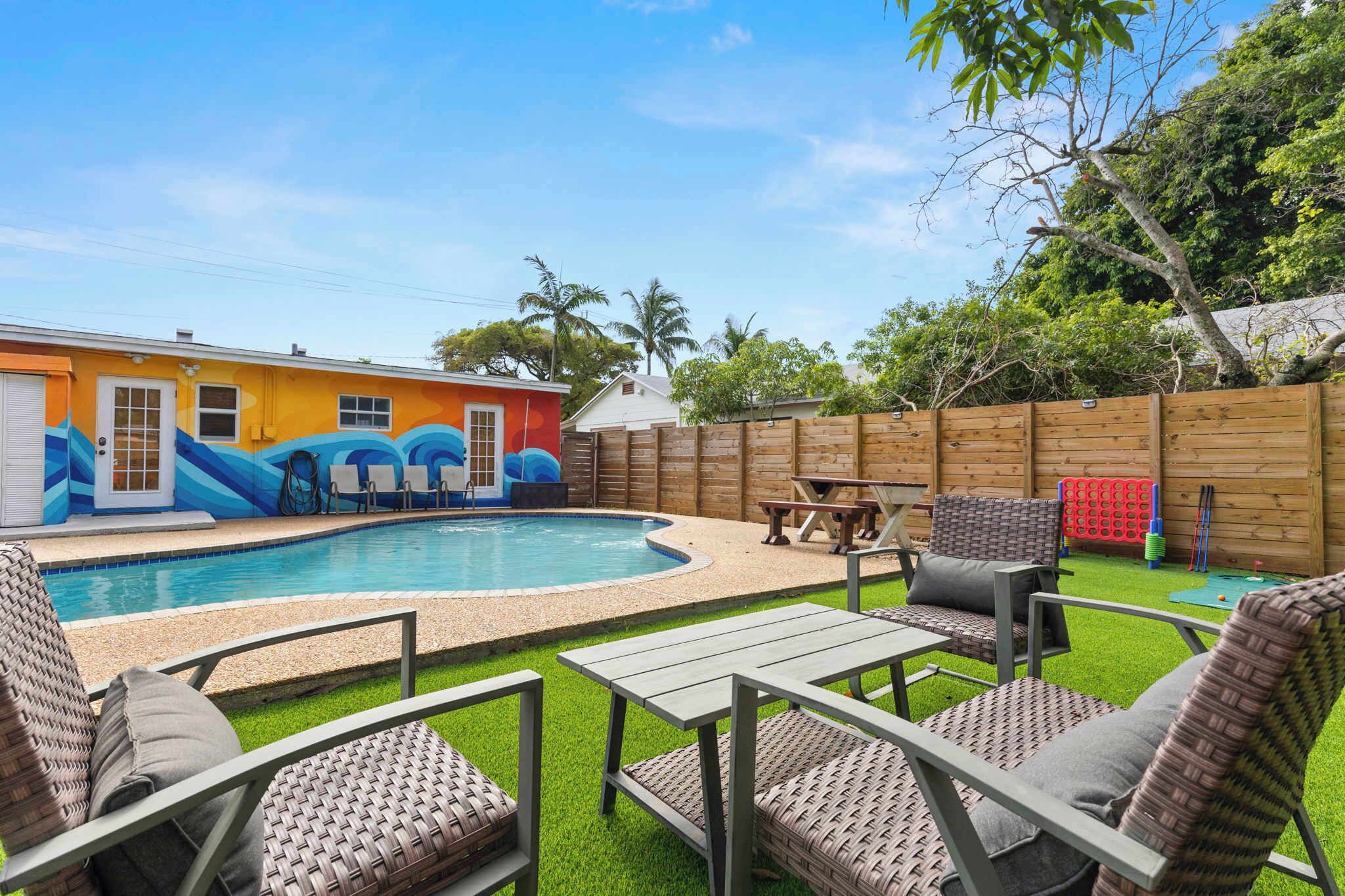 A backyard with a swimming pool, outdoor furniture, and a wooden fence.