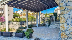 A covered outdoor area with stone flooring, potted plants, and a stone wall. - Apartment Ana by Interhome (Sv. Filip i Jakov)