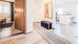 A modern apartment with a wooden door, a bench, a kitchen area, and a dining space. - Apartment Ana by Interhome (Sv. Filip i Jakov)