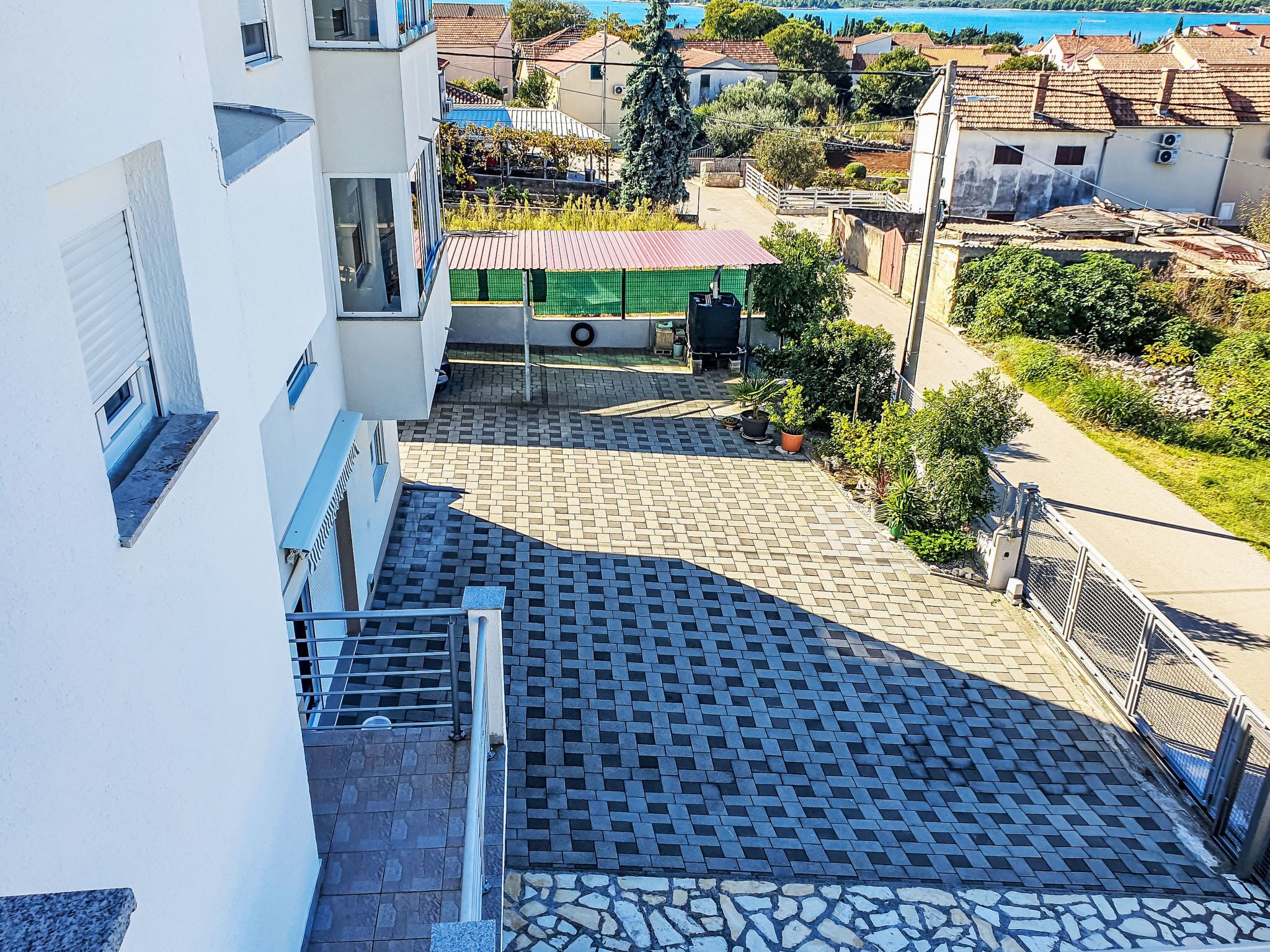 Zona residencial con patio empedrado, construcción con techo verde y vista a un cuerpo de agua.