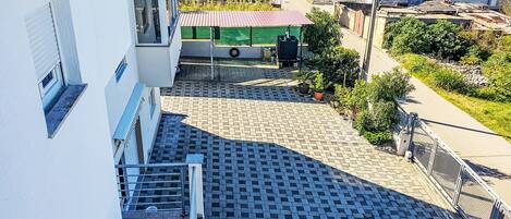Zona residencial con patio empedrado, construcción con techo verde y vista a un cuerpo de agua.