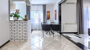 Ein modernes Wohnzimmer mit Essbereich, Kamin und großem Fenster mit Vorhängen.