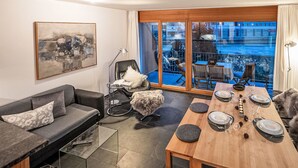 A modern living room with a sofa, a dining table set for four, and a balcony with a view of the city. - Chesa Promulins by Interhome (Samedan)