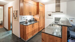 A modern kitchen with wooden cabinets, granite countertops, and stainless steel appliances. - Chesa Promulins by Interhome (Samedan)