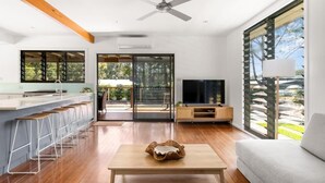 A modern living room with a wooden floor, a TV, a sofa, and a coffee table. - Tin & Timber by Charlesworth (Coffs Harbour)
