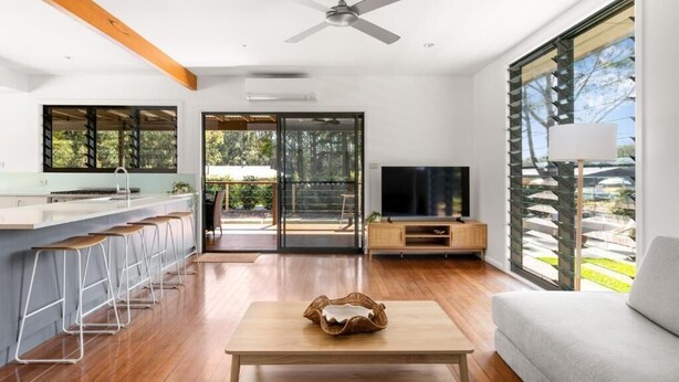 Una sala de estar moderna con suelo de madera, un televisor, un sofá y una mesa de centro.