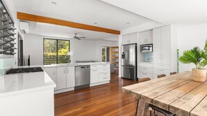 Una cocina moderna con gabinetes blancos, electrodomésticos de acero inoxidable y una mesa de comedor de madera.