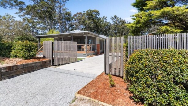 A modern house with a covered porch, a fenced yard, and a gravel driveway. - Tin & Timber by Charlesworth (Coffs Harbour)