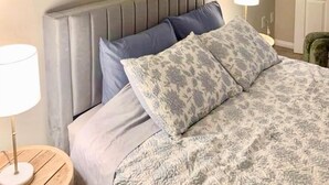 Una camera da letto con un letto, una testiera, un punto luce a parete e una porta.