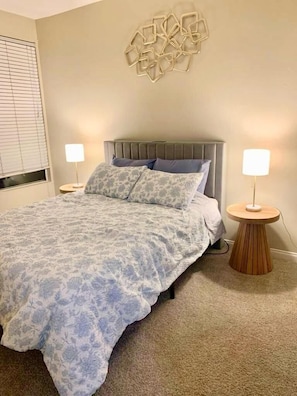 A bedroom with a bed, two bedside tables, a wall-mounted light fixture, and a window with blinds. - Ocean breeze retreat luxury 1B unit in Marina del Rey (Marina del Rey)