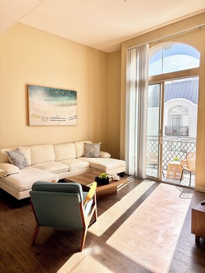 A living room with a beige sofa, a coffee table with a plant, and a view of a balcony with outdoor furniture. - Ocean breeze retreat luxury 1B unit in Marina del Rey (Marina del Rey)