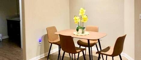 Un coin repas avec une table ronde, quatre chaises et un vase rempli de fleurs jaunes.