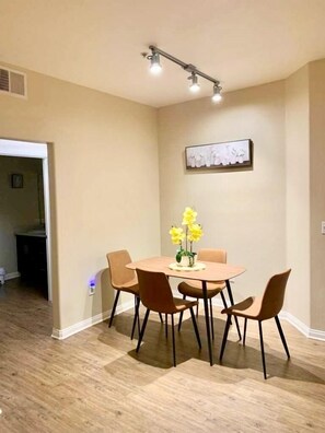 A dining area with a round table, four chairs, and a vase of yellow flowers. - Ocean breeze retreat luxury 1B unit in Marina del Rey (Marina del Rey)