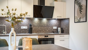 Et moderne køkken med granitbordplader, indbygget ovn og spiseplads med bord og stole.