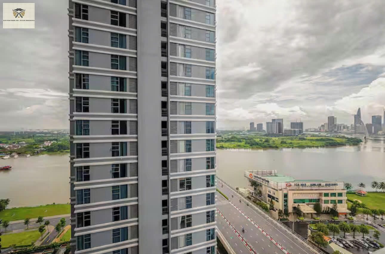 A high-rise building with a view of a river and a city skyline in the background.