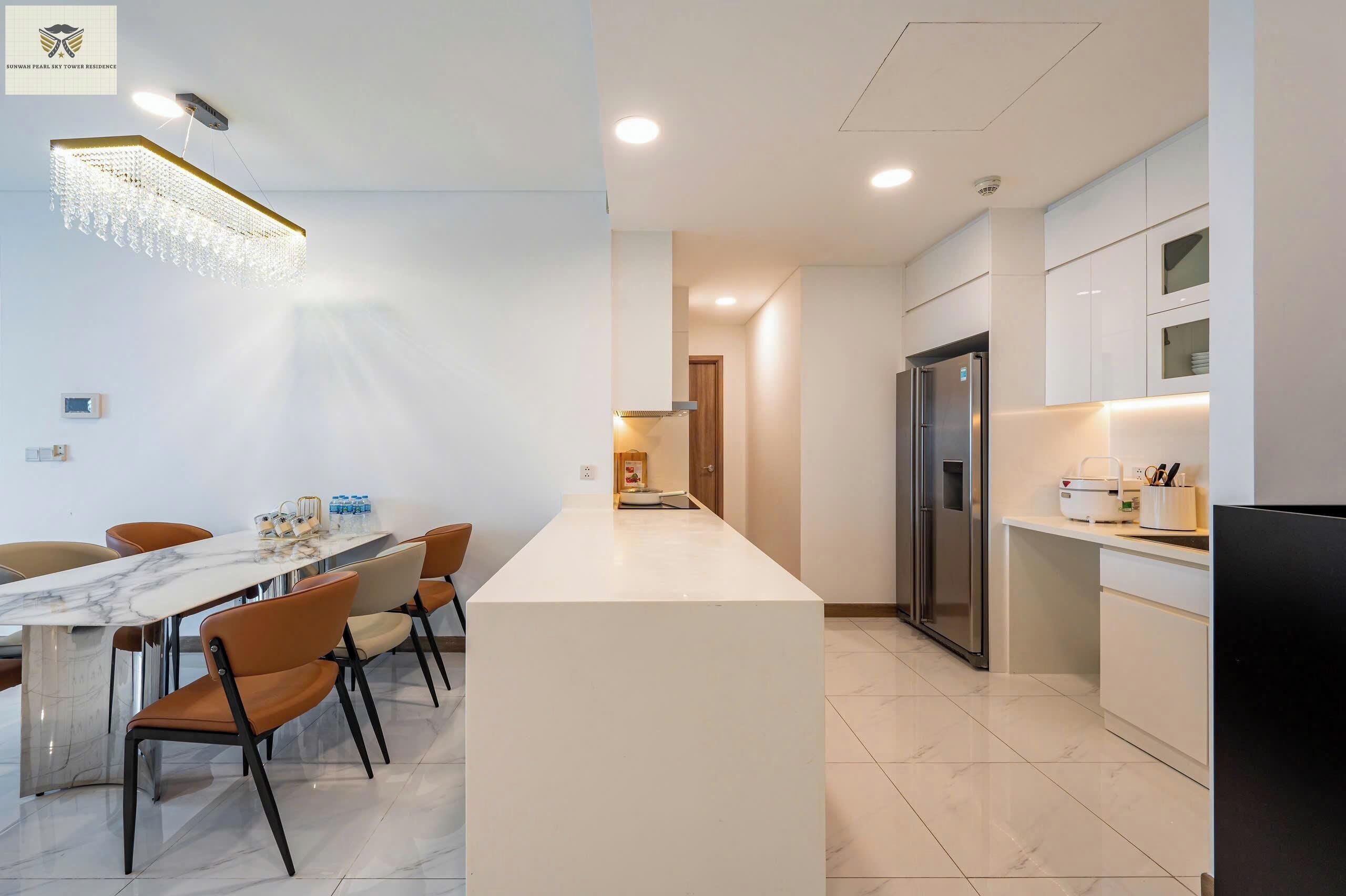 A modern kitchen with white cabinets, a stainless steel refrigerator, and a marble island.