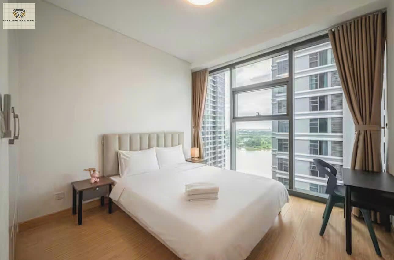Een hotelkamer met een groot bed, een bureau en uitzicht op de stad door een groot raam.
