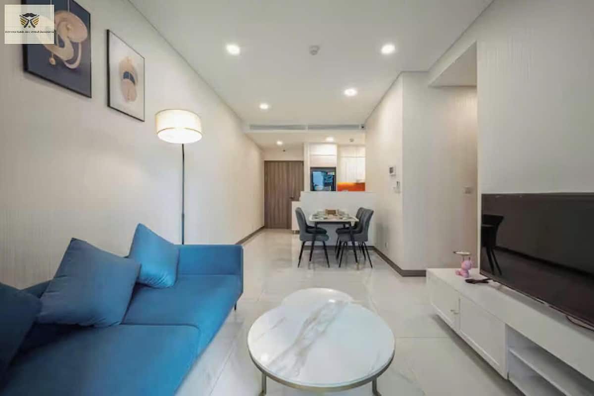 Un salon moderne avec un canapé bleu, une table basse blanche et un téléviseur à écran plat.