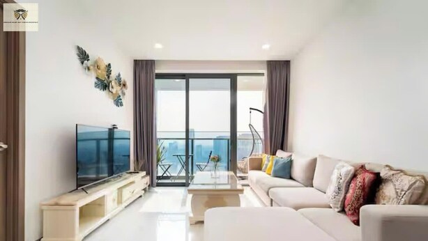 Ein modernes Wohnzimmer mit Flachbildfernseher, einer Couch, einem Couchtisch und einem Balkon mit Stadtblick.