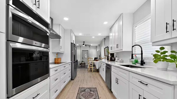 Una cocina moderna con gabinetes blancos, electrodomésticos de acero inoxidable y una isla central con fregadero.