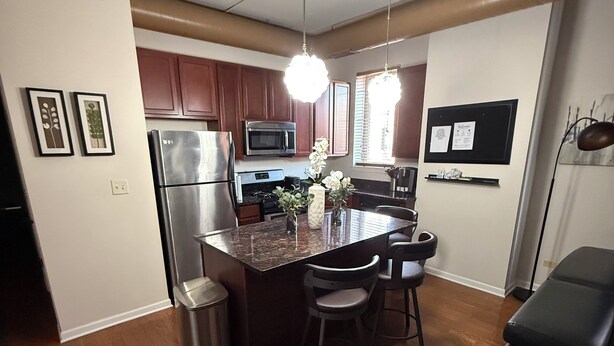 Una cocina moderna con armarios de madera, electrodomésticos de acero inoxidable y una isla central con taburetes de bar.
