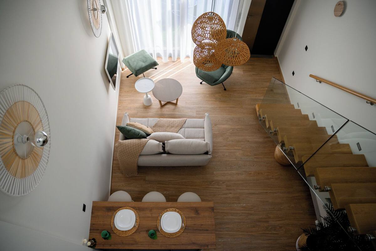 A modern living room with a sofa, a dining table with plates, a staircase, and a green chair.