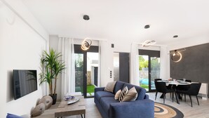 Een moderne woonkamer met een bank, salontafel en een eethoek.