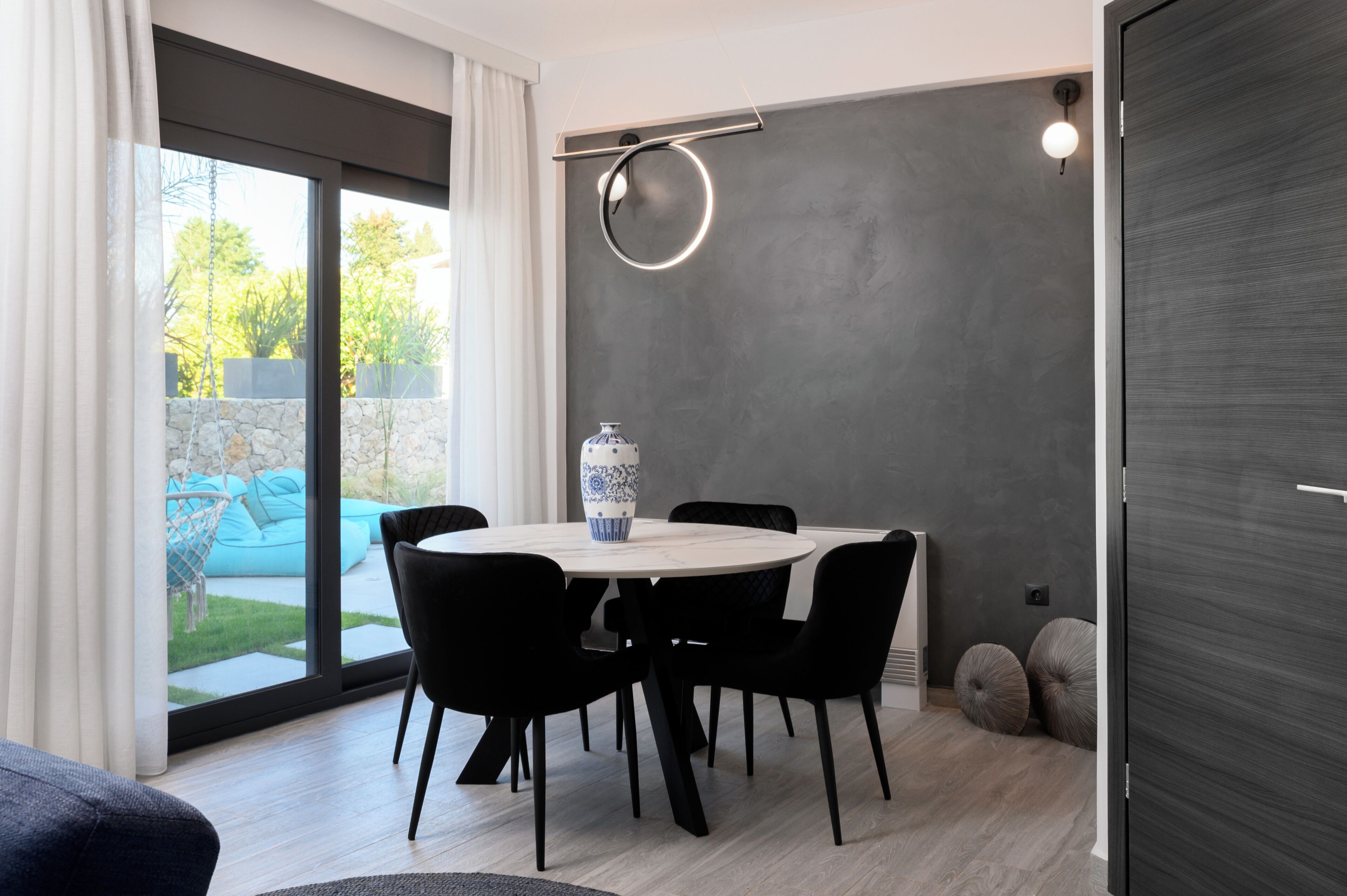 A modern dining area with a round table, black chairs, and a decorative vase.