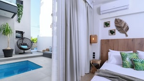 Een moderne hotelkamer met een groot bed, een klein zwembad en een balkon met een hangstoel.