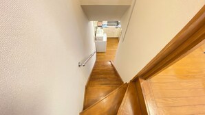 A narrow staircase leading to a kitchen area with a washing machine and a sink. - AkiraHome Tsutenkaku West (Osaka)