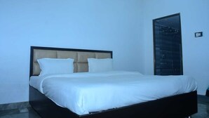 Ein ordentlich bezogenes Bett in einem schlicht und modern eingerichteten Raum.