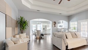 A spacious living area with a large sofa, a dining table, and a kitchen in the background. - Family Retreat w/Pool & Game Room/Sleeps 10 (Dallas)